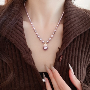 Détail d'un collier élégant plaqué or avec perles violettes et pendentif en cristal brillant