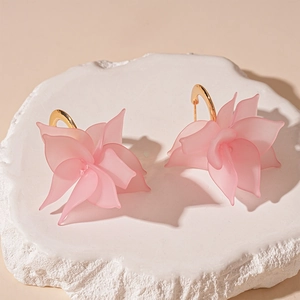 Macro detail of pink acrylic flower earrings with 3D petals and golden metal hooks