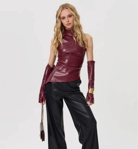 Détail du haut sans manches en similicuir bordeaux avec gants longs et pantalon noir large