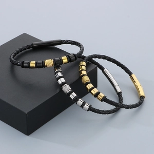 Detailed view of three-piece men's woven leather bracelets with steel beads on a black box