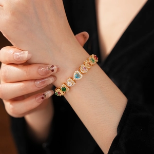 Macro shot of gold heart bracelet featuring vibrant multi-colored zircon gemstone inlay