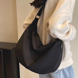 Waterproof black nylon dumpling crossbody bag shown on model in a minimalist setting