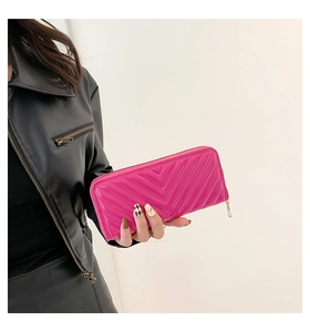 Close-up of hand-held rose pink long wallet with V-shaped quilting and gold zipper