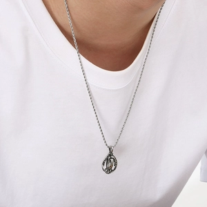 Detail of vintage punk titanium steel pendant with cross pattern on a twisted rope chain