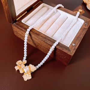 Detail view of pearl necklace with gold flower pendant in a wooden jewelry gift box