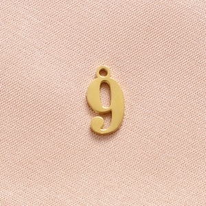 Close-up of polished gold stainless steel number 9 charm for necklaces and bracelets
