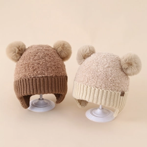 Dettagli della trama a maglia e pompon di peluche sui berretti invernali per neonati