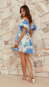 Détail d'une robe courte fleurie bleue avec col bardot et ourlet à volants