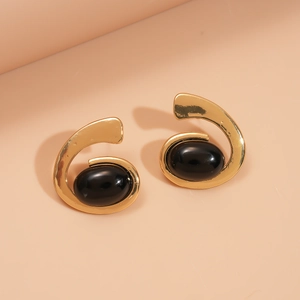 Détail de boucles d'oreilles spirales dorées avec de grandes pierres ovales noires brillantes
