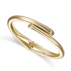 Detail of minimalist gold-plated bangle with internal spring hinge and polished finish