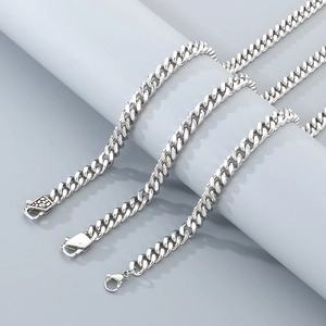 Close-up of silver Cuban link necklace with lobster clasp on a cylindrical display stand