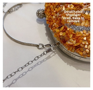 Detail of detachable metal chain strap on orange pumpkin-shaped rhinestone evening bag