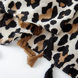 Detailed view of leopard print scarf featuring woven texture and fringe tassel edges