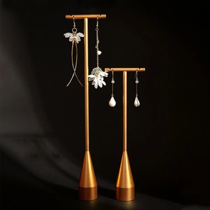 Creative metal jewelry display stand featuring flower and pearl earrings on black background
