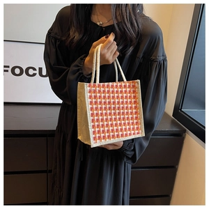 Close-up of woman holding linen handbag with orange houndstooth woven pattern