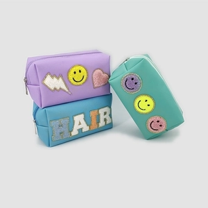 Detail of PU leather makeup bags with chenille letter patches and metal zipper closures