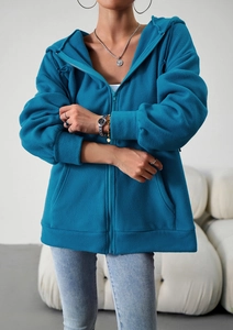 Detailed shot of a blue fleece zip-up hoodie featuring a loose fit and practical side pockets