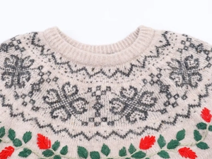 Close-up of Fair Isle knit sweater with red flower embroidery and grey geometric patterns