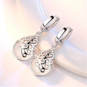Gros plan de boucles d'oreilles gouttes avec motifs évidés en argent et incrustations d'opale