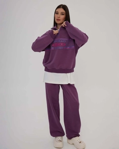 Detail of purple hoodie set with half-zip collar and wide-leg trousers on a model