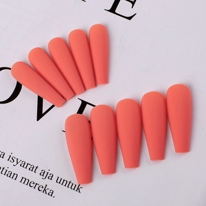 Flat lay of matte orange long ballerina press-on nails on aesthetic paper background