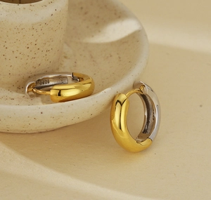 Macro detail of S925 sterling silver two-tone hoop earrings on a ceramic dish