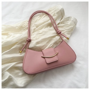 Top view of pink leather shoulder bag with gold curved metal buckle on white fabric