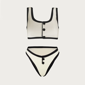 Detail of ribbed two-piece swimsuit with black trim and decorative buttons