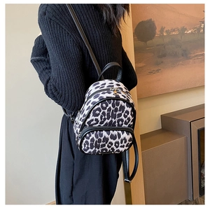 Close-up of stylish leopard print mini backpack with leather straps and zip pocket
