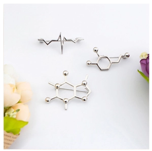 Detailed close-up of silver metal brooches featuring molecular structures and heartbeat waves
