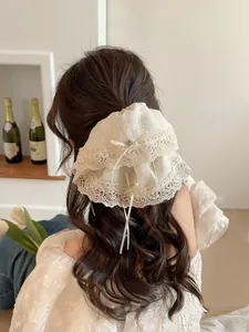 Detail of white lace hair clip with pearls and long ribbons on wavy brown hair