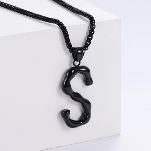Vue détaillée du pendentif lettre S 3D noir avec chaîne sur support d'exposition