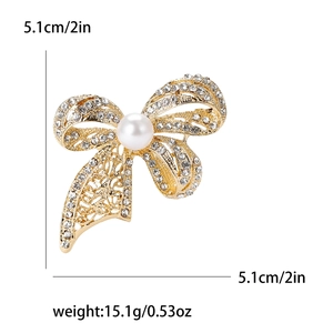 Elegant gold bow brooch with sparkling rhinestones and a large pearl on white background