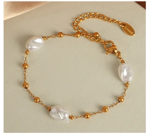 Detail of gold stainless steel chain bracelet with irregular white pearls and lobster clasp