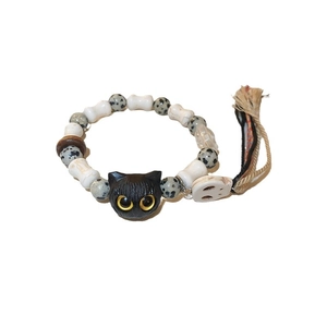 Handcrafted ceramic bead bracelet with black cat pendant and bohemian tassel on white surface