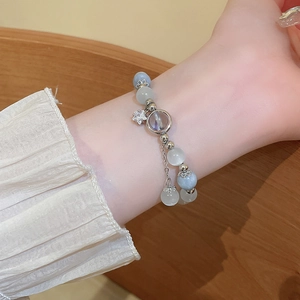 Detailed view of the beaded star charm bracelet with cat eye stones on a wrist
