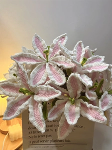 Close-up of handmade crochet lily bouquet in paper bag with decorative candles