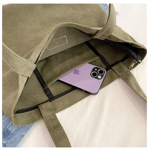 Detailed interior of the green canvas tote bag featuring neat stitching and inner pockets