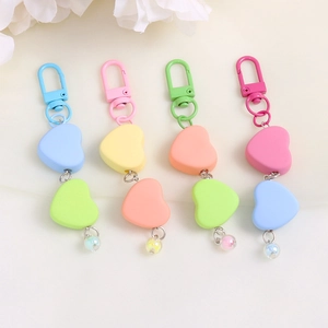 Close-up of heart-shaped keychains in blue, pink, yellow and green colors with star clips