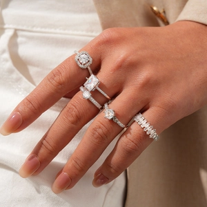 Close-up of five silver rings with round and square cubic zirconia stones worn together