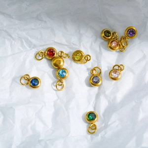 Colorful zircon zodiac stone charms with gold stainless steel plating on white paper