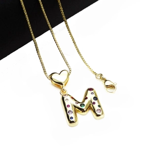 Close-up of gold M letter pendant with multi-color zircons on a delicate box chain