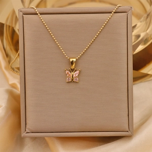 Detail view of 18K gold butterfly necklace with pink gemstone on brown gift box