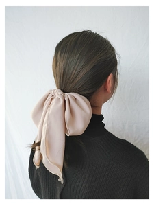 Detail of light pink fabric bow hair tie with elegant wavy edges on a ponytail