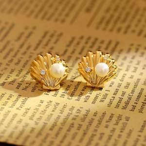 Elegant shell-shaped stud earrings with white pearl and gold plating on vintage book pages