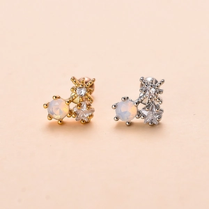 Macro view of gold and silver screw-back ear studs with opal and star zircon stones