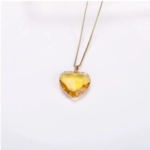 Detail of yellow heart-shaped crystal pendant with gold-plated prong setting on a chain