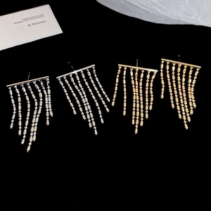 Close-up of gold and silver metal tassel fringe drop earrings on a black background