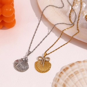 Detail of 18K gold and silver scallop pendants with starfish and bow designs