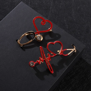 Macro view of ECG heartbeat and stethoscope medical brooches with red zircons